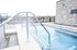 Inviting outdoor pool with modern stainless-steel railings and a stylish stone wall backdrop.