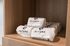 Luxury bathroom display with elegant Altura branded towels neatly stacked on wooden shelves.