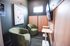 Cozy room with modern decor, featuring two plush green chairs, a wall-mounted TV, and stylish artwork, perfect for relaxation or intimate gatherings.