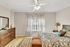 Elegant bedroom with stylish decor, featuring a wooden dresser, patterned curtains, and a cozy bed with vibrant bedding.