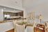 Elegant kitchen and dining area with sleek dark cabinets, a stainless steel fridge, and a cozy round glass table set for four.