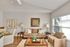 Inviting living room with modern decor, cozy beige sofas, and abundant natural light from large windows.