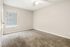 Bright and inviting carpeted bedroom with natural light, featuring a ceiling fan and neutral walls.