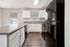 Elegant kitchen with modern black appliances, sleek dark countertops, and bright white cabinetry complemented by natural light and stylish blinds.