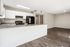 Bright open-plan kitchen and living area with modern white cabinets, sleek countertops, and stylish wood flooring.