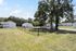 Charming residential complex with lush grassy areas, mature trees, and white buildings under a clear blue sky.