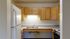 Bright kitchen with modern wooden cabinets, sleek countertops, double sink, and spacious refrigerator for an inviting culinary space.