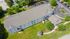 Aerial view of a charming apartment complex with well-maintained lawns, surrounded by lush greenery and ample parking.
