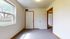 Bright and airy room featuring two doors, plush carpeting, and a large window with a serene garden view.
