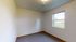 Bright and inviting room with a large window offering a serene view of the lush outdoors; perfect for a cozy bedroom or inspiring home office.