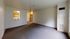 Spacious living room with an open view of the cozy kitchen featuring modern wooden cabinets and sleek appliances.