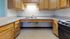 Inviting kitchen with warm wooden cabinetry, sleek countertops, double sink, and modern stovetop, emphasizing functionality and charm.
