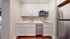 Contemporary kitchen with sleek stainless steel appliances, pristine white cabinetry, and elegant wooden flooring.
