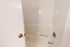 Elegant bathroom featuring a modern white bathtub with sleek chrome fixtures and pristine white walls.