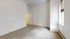 Spacious room with high ceilings and large window, inviting natural light and offering a cozy ambiance.
