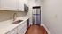Sleek modern kitchen with pristine white cabinetry, stainless steel appliances, and elegant wooden flooring.