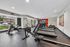 Modern fitness center equipped with state-of-the-art treadmills, stationary bikes, and rowers, offering a vibrant and dynamic workout space with large windows and motivational decor.