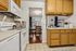 Inviting apartment kitchen with modern appliances, light wood cabinets, and a peek into a cozy dining area with large windows.