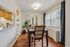 Inviting dining room with elegant table and chairs, featuring natural light from large windows and a view into the modern kitchen area.