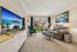 Inviting living room with plush carpet, stylish couch, vibrant artwork, and large windows offering ample natural light.