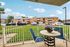 Charming apartment balcony view with patio furniture overlooking a well-maintained grassy courtyard and parked cars.