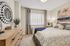 Elegant bedroom with modern decor, featuring a stylish mirror, cozy bed with plush pillows, and a chic dresser.