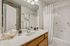 Modern bathroom with elegant fixtures, large mirror, and a pristine white bathtub in a cozy apartment.