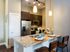 AMLI at Mueller kitchen with stools at a granite counter with dark wood cabinets and stainless steel appliances in background