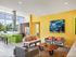 AMLI at Mueller clubroom with grey couches and chairs against a yellow wall with barstools at a green counter in background