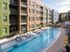 Exterior view of pool at AMLI at Mueller with blue umbrellas and white lounge chairs with facing building facade