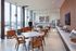 AMLI West Loop social lounge with dining tables, brown leather seating, a kitchen counter, floor-to-ceiling windows, and a man walking past