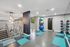 Fitness center at AMLI Dadeland apartments with medicine balls and kettle bells and yoga mats hung up on the wall and mirrors