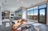 Spacious lounge area with large windows, bar seating, plush tan sofa over a decorative rug at AMLI Frisco Crossing apartment sky lounge.