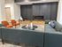 Modern lounge area with sleek sofas, vibrant orange armchairs, and a cozy fireplace, perfect for relaxation and entertainment.