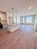 Chic open-plan apartment kitchen with island seating, stylish light fixtures, and expansive living area featuring elegant flooring and abundant natural light.