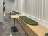 Contemporary seating area featuring sleek wooden benches with green cushions and modern tabletops, ideal for relaxing or socializing.