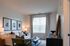 Inviting living room with a cozy white sofa, elegant decor, and abundant natural light from large windows, perfect for relaxation.