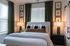Elegant bedroom with a plush bed, decorative pillows, stylish bedside lamps, and sophisticated wall art.