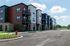 Modern apartment building with colorful exterior, spacious balconies, and abundant parking under a clear sky.