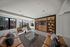 Modern living room with large windows, stylish wooden shelving, and comfortable seating, offering a bright and inviting space with urban views.
