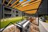 Elegant outdoor communal space with modern seating, wooden pergola, and lush greenery, perfect for relaxation and gatherings.