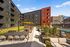 Modern apartment complex featuring a vibrant outdoor patio and lounge area with stylish furniture and lush greenery.