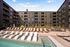 Modern apartment complex showcasing a luxurious pool area with stylish lounge chairs and inviting outdoor spaces.