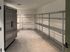 Spacious utility room with sleek stainless steel refrigerator and ample metal shelving, ideal for storage and organization.