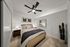 Inviting bedroom with cozy bedding, modern ceiling fan, stylish decor, and a vibrant potted cactus.