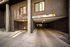 Modern apartment building entrance with secure parking area, framed by elegant brickwork and large windows.