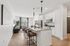 Modern open-concept kitchen and living room with sleek white cabinets, stylish pendant lighting, and a cozy seating area perfect for relaxation.