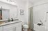 Bright and modern bathroom featuring elegant white cabinets, a sleek countertop, and a stylish shower with a green curtain.