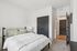 Bright, modern bedroom featuring a plush, cozy bed with elegant linens, stylish dark doors, and a warm, inviting atmosphere.