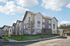 Modern apartment complex with stylish architecture, featuring large windows and balconies, set against a bright sky.